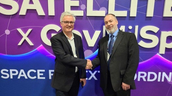 Miklos Tomka and Dana Irvin shaking hands in front of a Satellite x GovMilSpace backdrop.